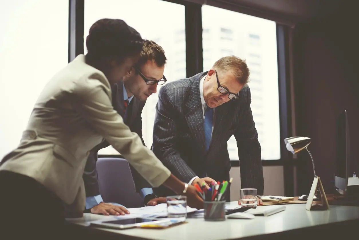 Three men in suits and ties working on a project.